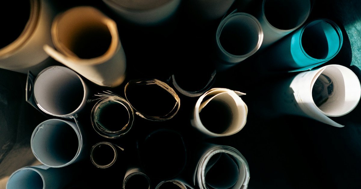 Rolls of drawing paper standing on end, seen from above in low light.