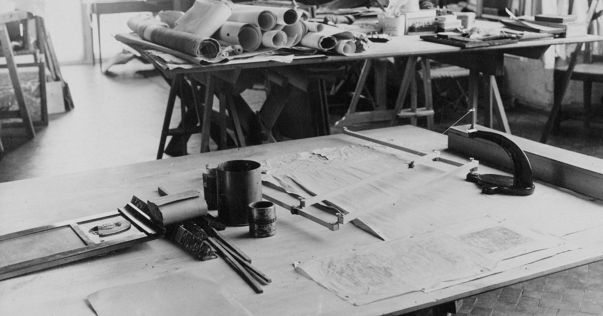 A drafting table with rolled drawing sheets, set squares and a parallel rule.