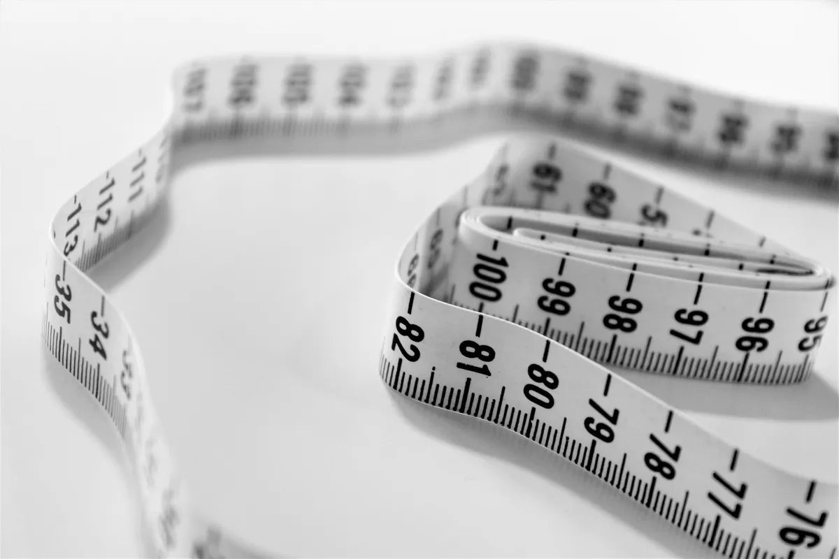 A tape measure lying in loose loops, photographed in black and white.