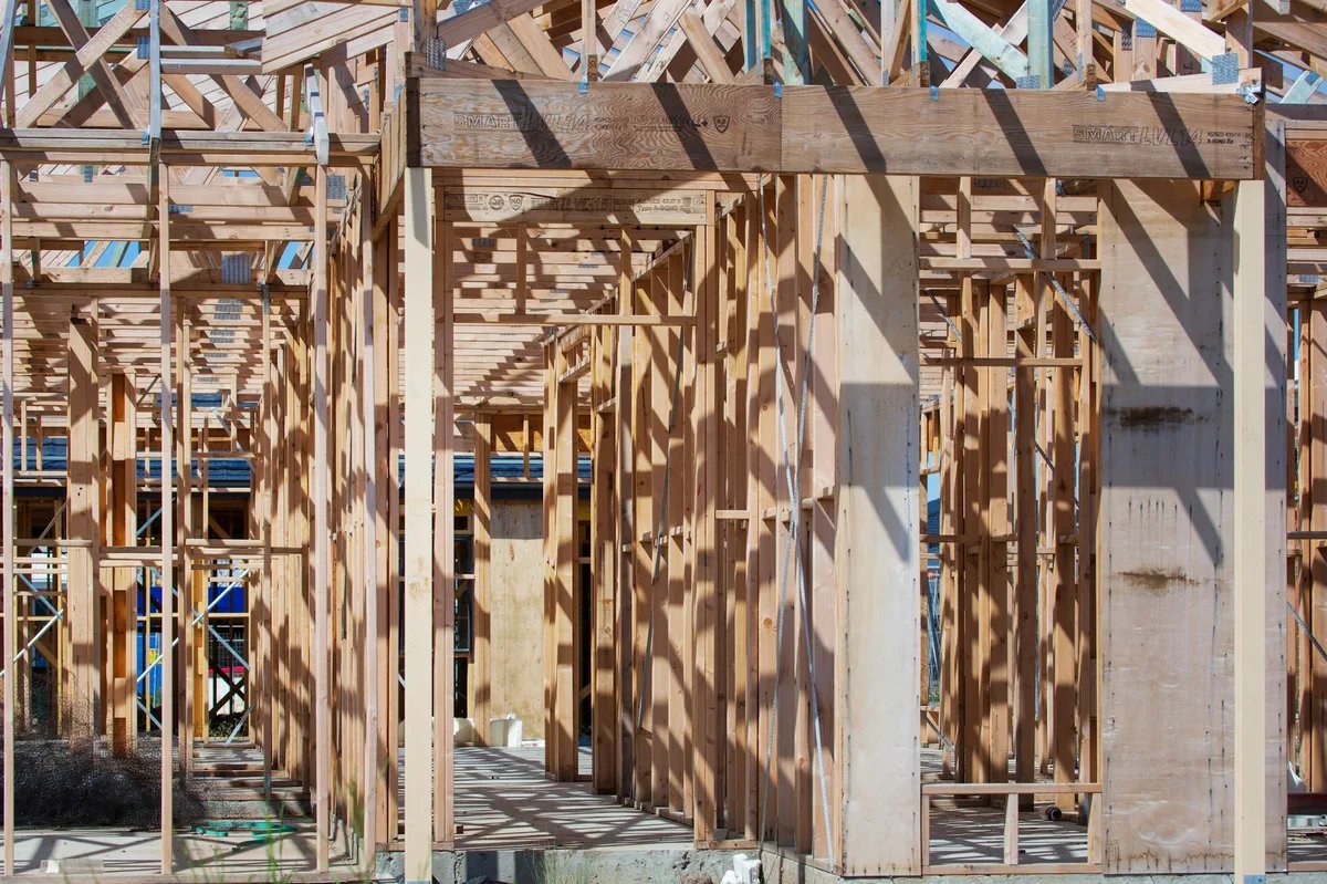 Timber stud walls and headers of a house frame standing on a slab before any board goes on.