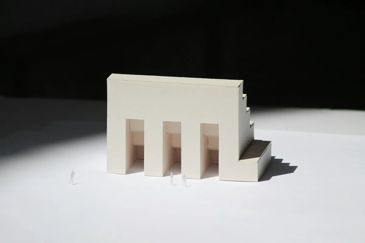 A white physical model of a building standing on a plain white surface.
